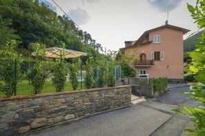 Ein zweigeschossiges Haus mit einer Steinmauer, einem gepflasterten Zugangsweg und einem grünen Rasen.