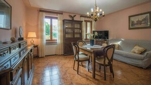 Ein Essbereich mit Holztisch, Stühlen, einer Deckenleuchte, einem Fernseher und einer Couch.