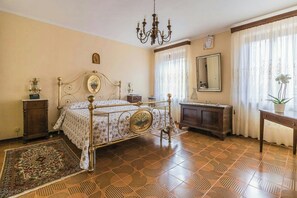 Ein Schlafzimmer mit einem Himmelbett, einer Chandelüster, einem Spiegel und einem Holzschrank.