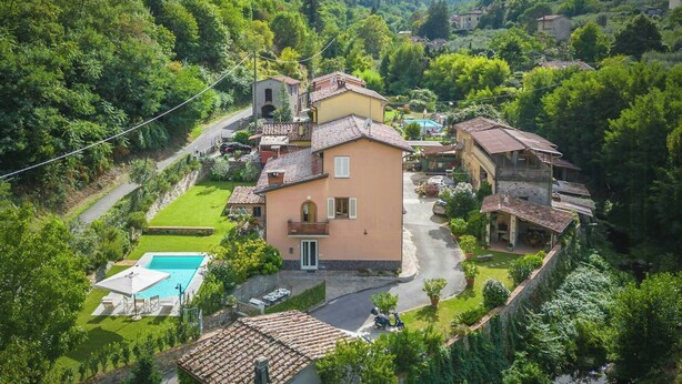 Eine Villa an einem Hang mit Swimmingpool, umgeben von üppiger Vegetation und einer Bergkulisse.