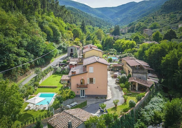 Eine Villa an einem Hang mit Swimmingpool, umgeben von üppiger Vegetation und einer Bergkulisse.