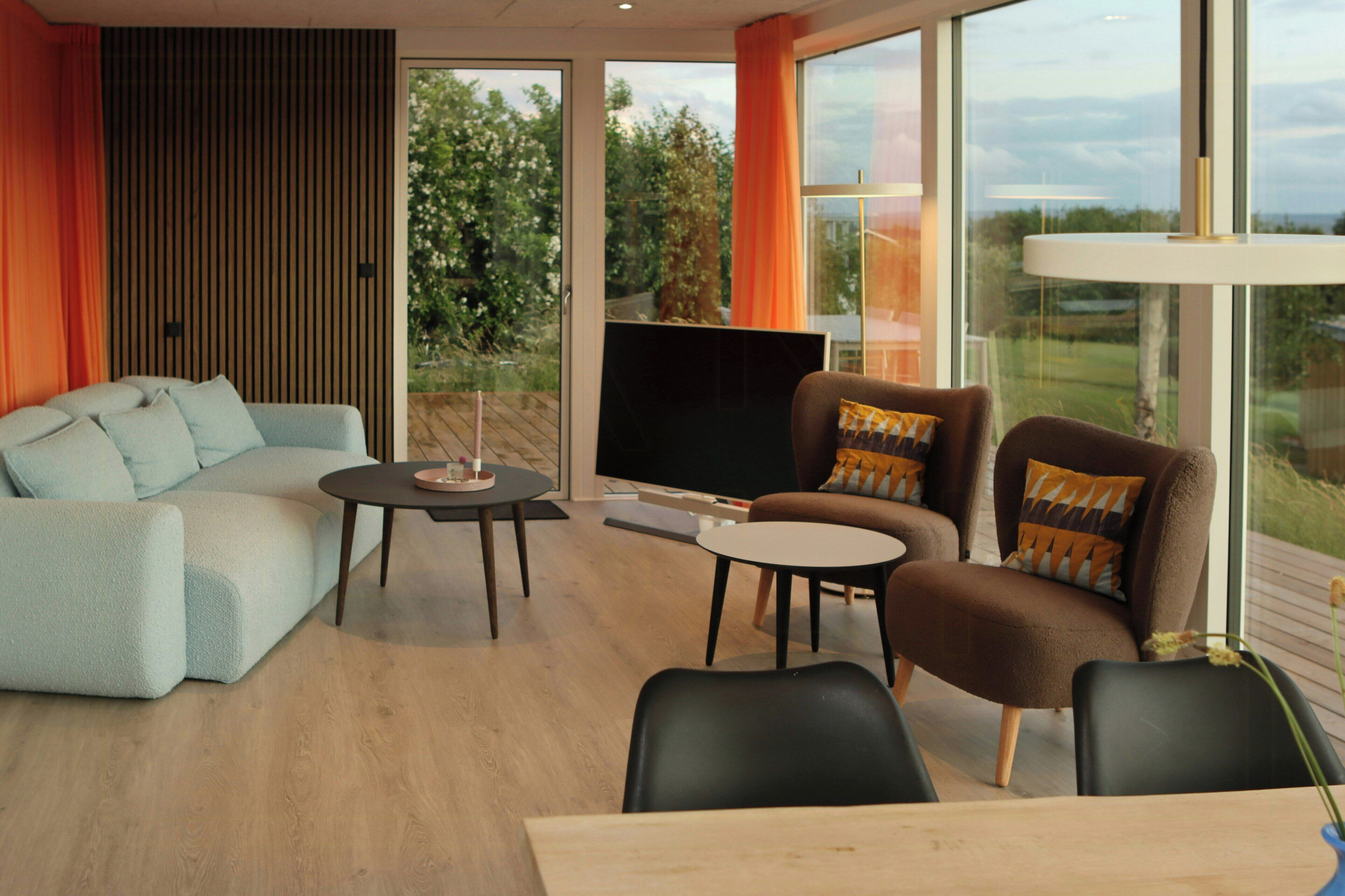 Una sala de estar moderna con sofá, sillones, una mesita de centro y televisión.