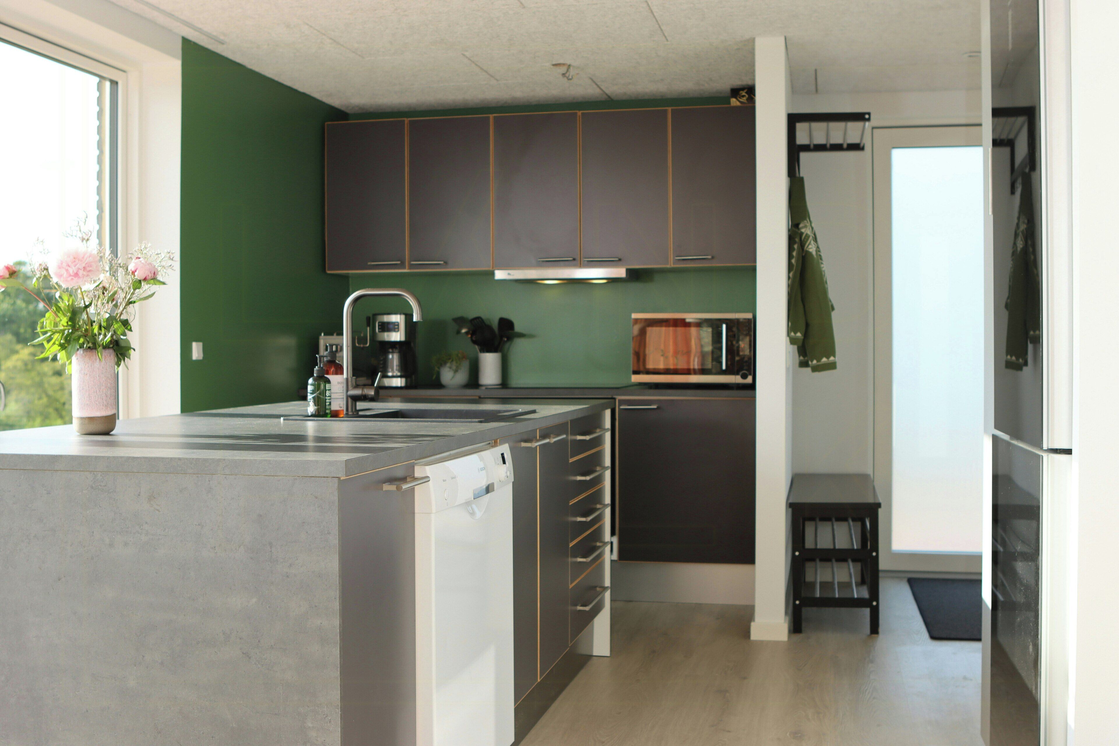 Une cuisine moderne dotée d’un grand îlot central, de meubles de couleur sombre et d’une fenêtre offrant une belle vue.