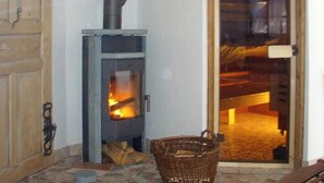 Una habitació amb una estufa de llenya, una cistella de vimet i una porta de fusta.