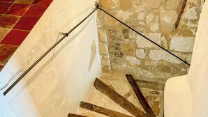 A staircase with stone walls, a red-tiled floor, and a black light fixture. - Village house with panoramic view in Venasque (Venasque)