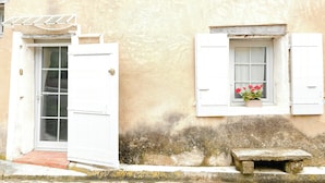 A building with a white door, a window with shutters, and a stone bench. - Village house with panoramic view in Venasque (Venasque)