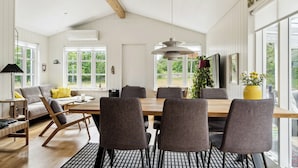 A spacious dining area with a wooden table and chairs, large windows, and a ceiling with exposed beams. - Here, time is tuned into intimacy and coziness (Hadsund)