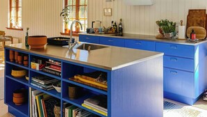 Eine Küche mit blauen Schränken, einer zentralen Kochinsel und einem Bücherregal voller Bücher.