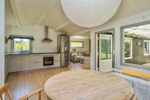 Eine moderne Küche mit Holzboden, einem runden Esstisch und einem großen Fenster.