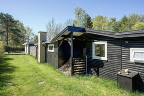 Eine Blockhütte mit Veranda, einem Fenster und einem kleinen, von einem Zaun umgebenen Außenbereich.