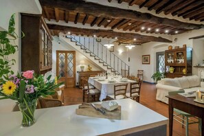 Ein Essbereich mit Tisch für vier Personen, eine Treppe und ein Wohnzimmer mit einer Couch.