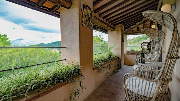 A covered outdoor area with wicker furniture, potted plants, and a view of greenery. - Giglio. Country villa with private pool near Lucca (Lucca)