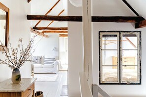 A room with a wooden ceiling, a white wall, and a window with a white frame.