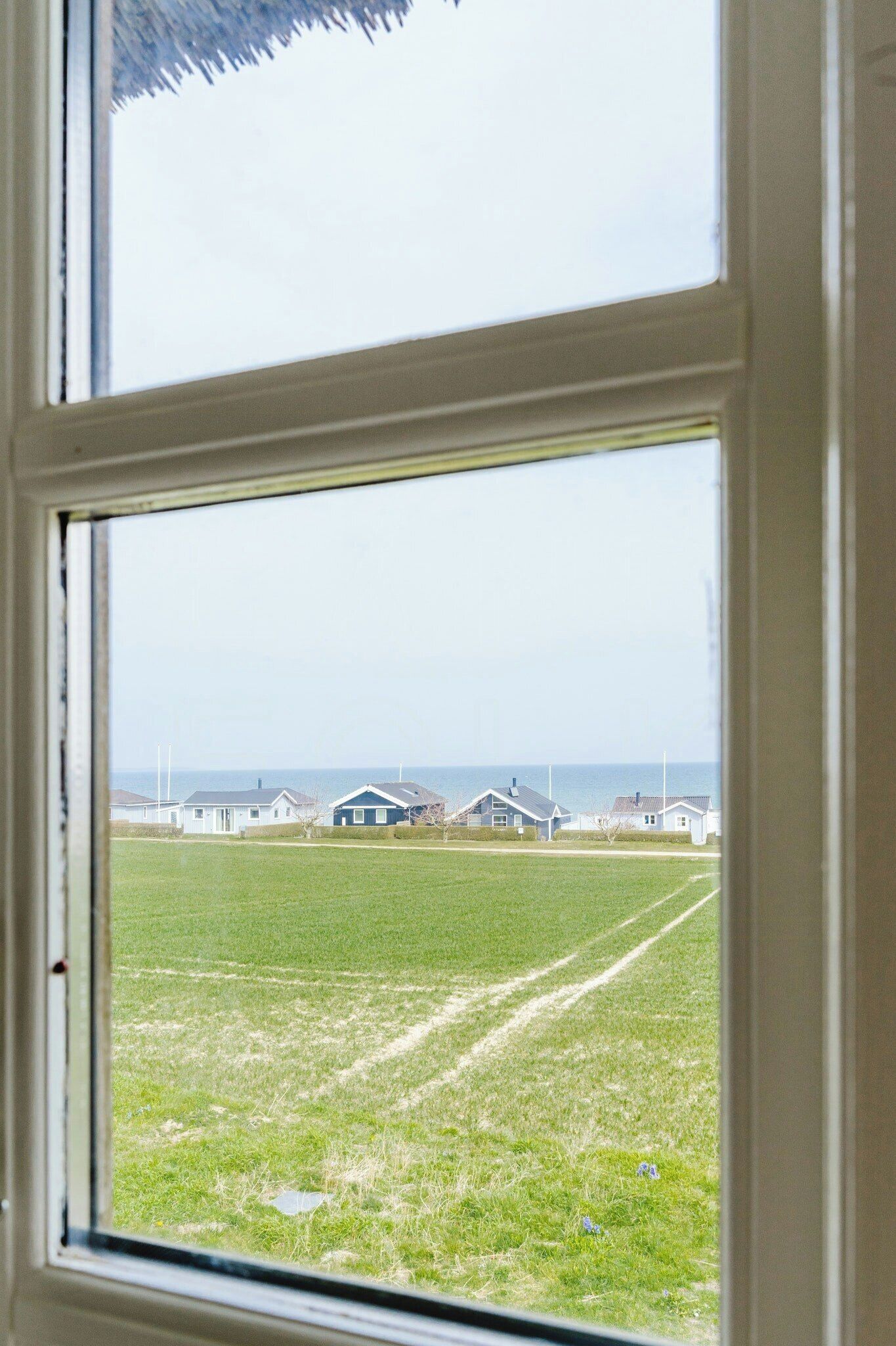 Vista per una finestra d'un camp de gespa amb cases a la distància.
