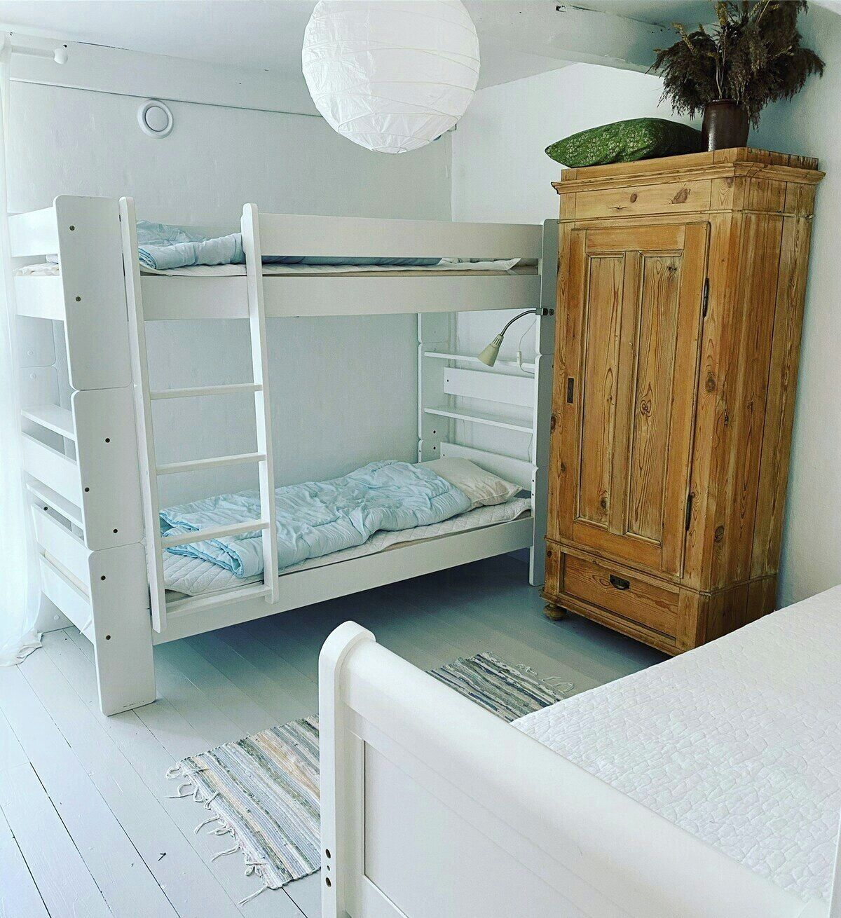 Una cama litera con un armario de madera y una lámpara colgante.