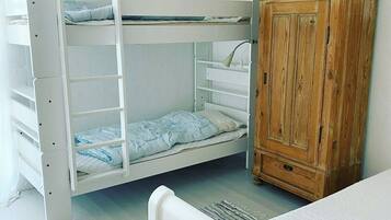 Una cama litera con un armario de madera y una lámpara colgante.