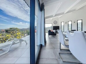 A modern hotel room with a large balcony, a sofa, and a TV. - Modern villa with sea views and infinity pool (Les Adrets-de-l'Estérel)