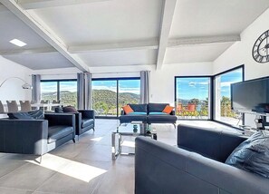 A modern living room with a sofa set, a coffee table, and a TV. - Modern villa with sea views and infinity pool (Les Adrets-de-l'Estérel)