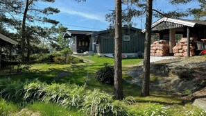 Ein rustikales Blockhaus mit Veranda, umgeben von einem grünen Rasen und Bäumen.