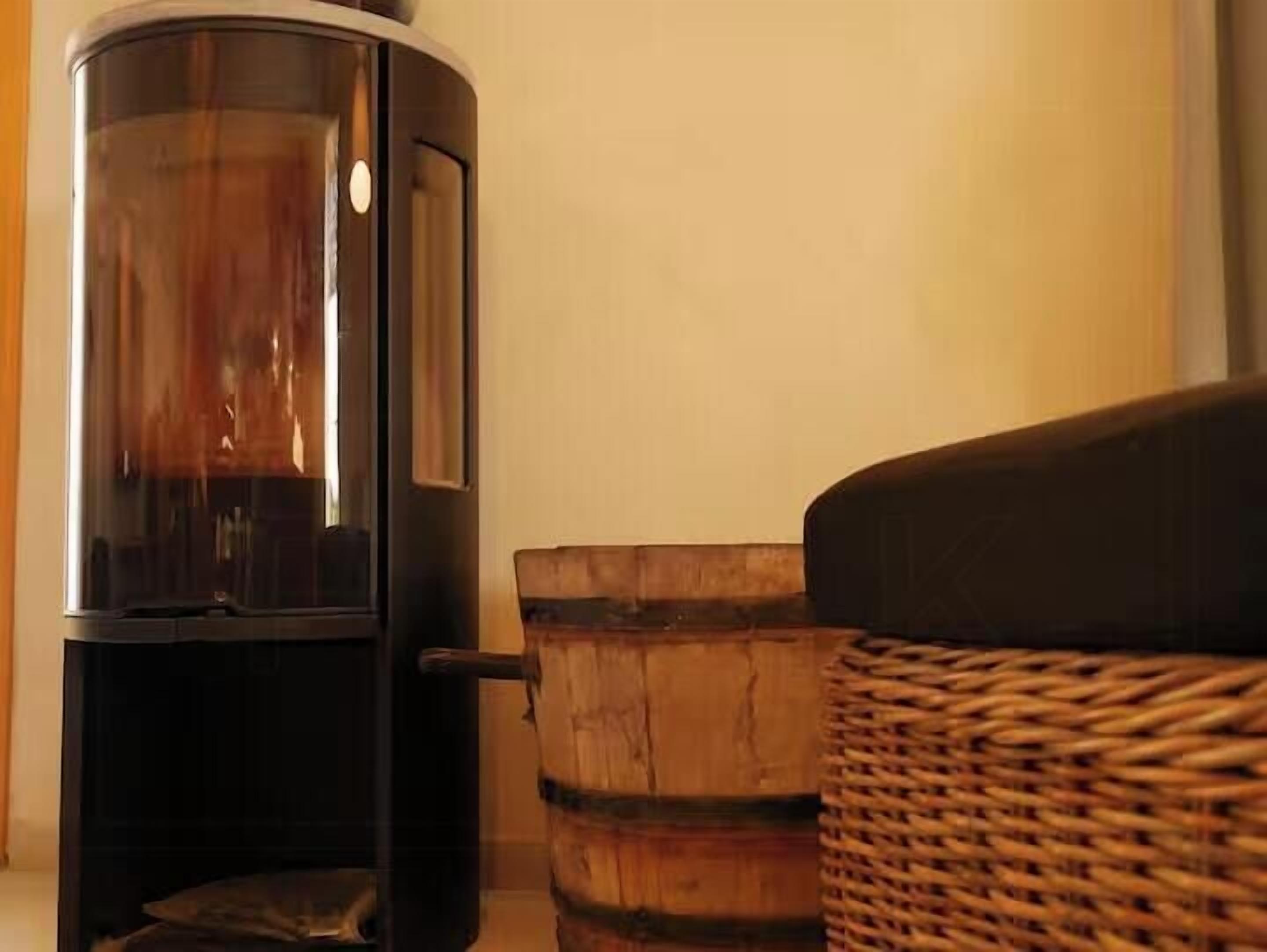 A room with a wood-burning stove, a wicker basket, and a dark-colored sofa.