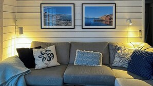 Un divano con cuscini decorati, un quadro incorniciato sopra e una lampada a parete.