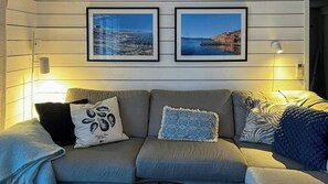 Ein Sofa mit gemusterten Kissen, ein gerahmtes Bild darüber und eine Wandlampe.
