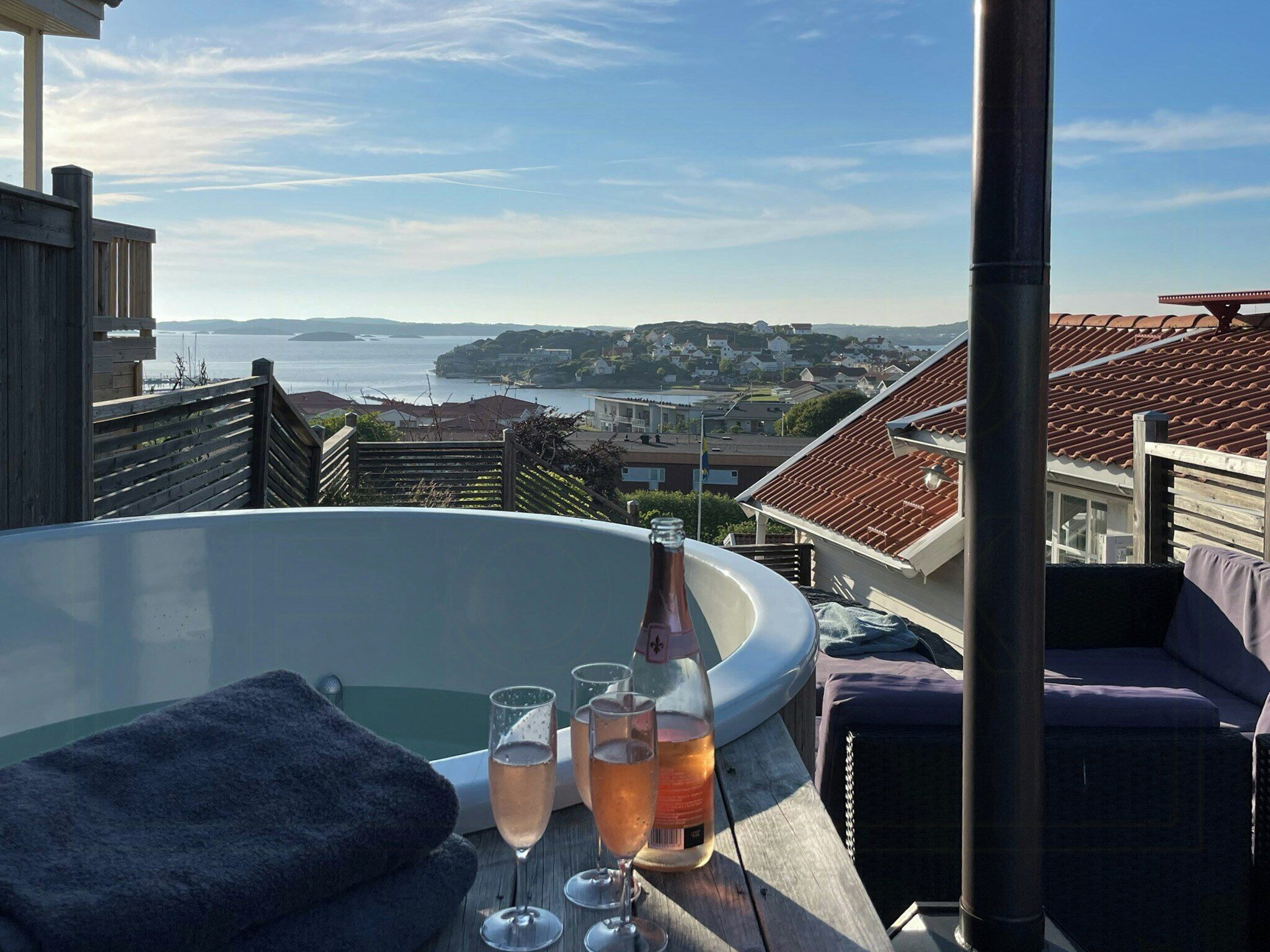 En balkong med ett bubbelbad, två glas med dryck och en flaska vin.