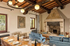 A dining area with a wooden table set for a meal, a blue sofa, and a fireplace.