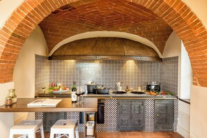 A kitchen with a brick arch, checkered backsplash, and modern appliances.