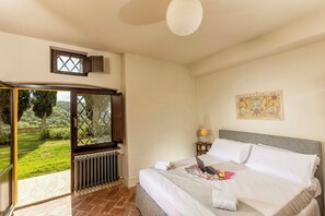 A bedroom with a bed, a laptop, a lamp, a window, and a radiator.
