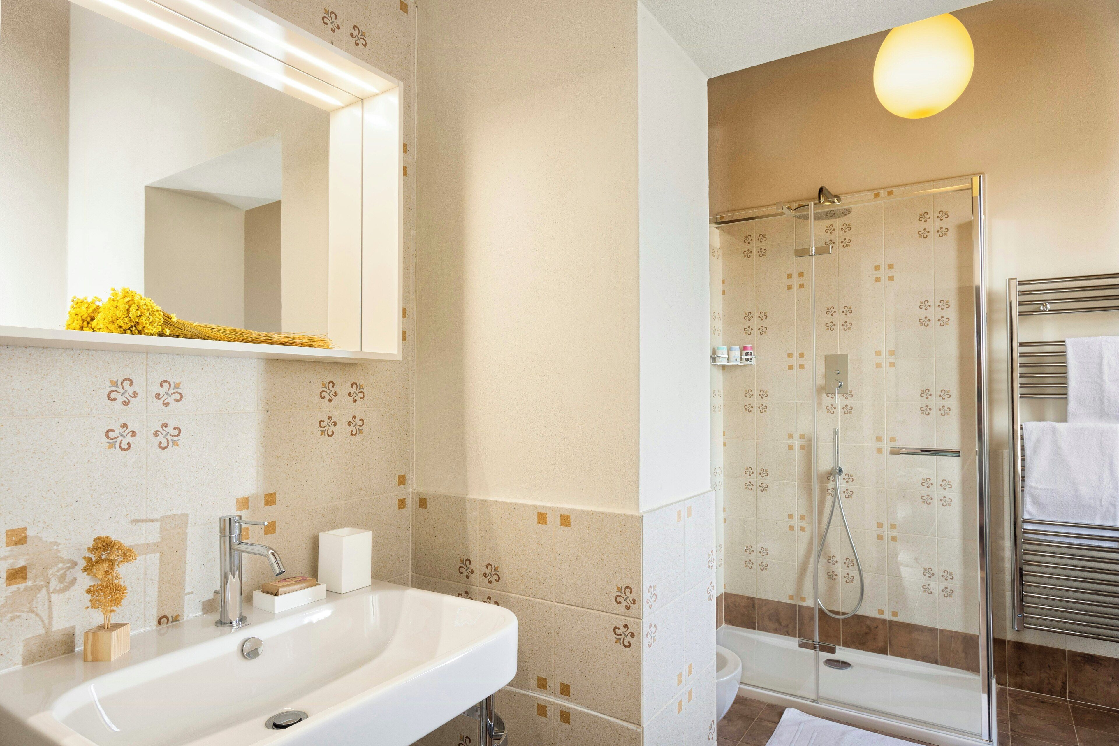Een badkamer met een wastafel, spiegel, douche en handdoekhouder.