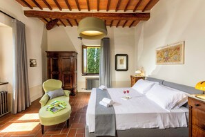 A hotel room with a bed, a chair, a window, and a painting on the wall.