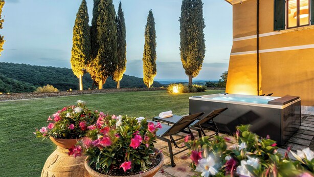 A spa area with a hot tub, lounge chairs, and potted plants.