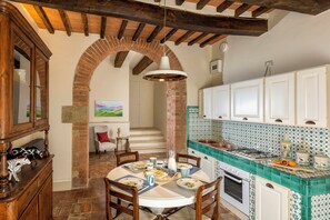 A kitchen with a brick archway, white cabinets, and a tiled backsplash.