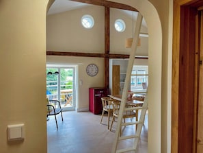 Ein Zimmer mit Holzboden, einer runden Uhr, einem roten Schrank und einem Tisch mit Stühlen.