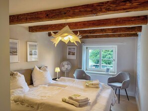 Ein Schlafzimmer mit Bett, Ventilator, Fenster und Stuhl.