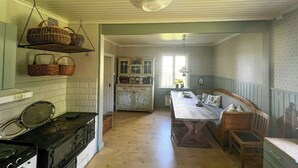 A kitchen with a stove, hanging baskets, and a dining area with a table and bench.