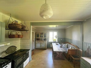 Uma cozinha com fogão, cestos suspensos e um espaço de refeições com mesa e banco.