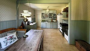 A kitchen with a dining area, wooden table, and hanging light fixture.