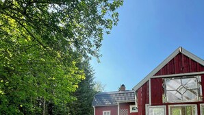 A red wooden house with a garden in front.