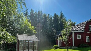A red barn, a wooden bench, a glass greenhouse, and a gravel garden.