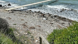 A wooden pier extending into a rocky shoreline with waves crashing onto it. - Summer house with panoramic sea views on Røsnæs (Kalundborg)