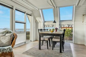 Un comedor con mesa, sillas y vistas amplias a través de grandes ventanales.
