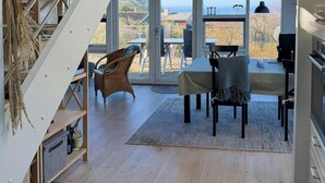 A modern interior with a staircase, dining area, and large windows offering a view. - Summer house with panoramic sea views on Røsnæs (Kalundborg)