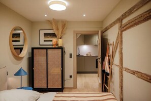 Ein Schlafzimmer mit Bett, Kleiderschrank, Spiegel und kleinem Schreibtisch mit Lampe.