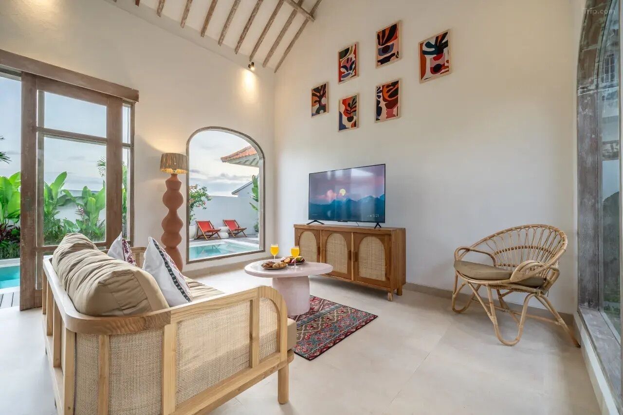 Una sala de estar con sofá, sillón, televisor y vista a la piscina.