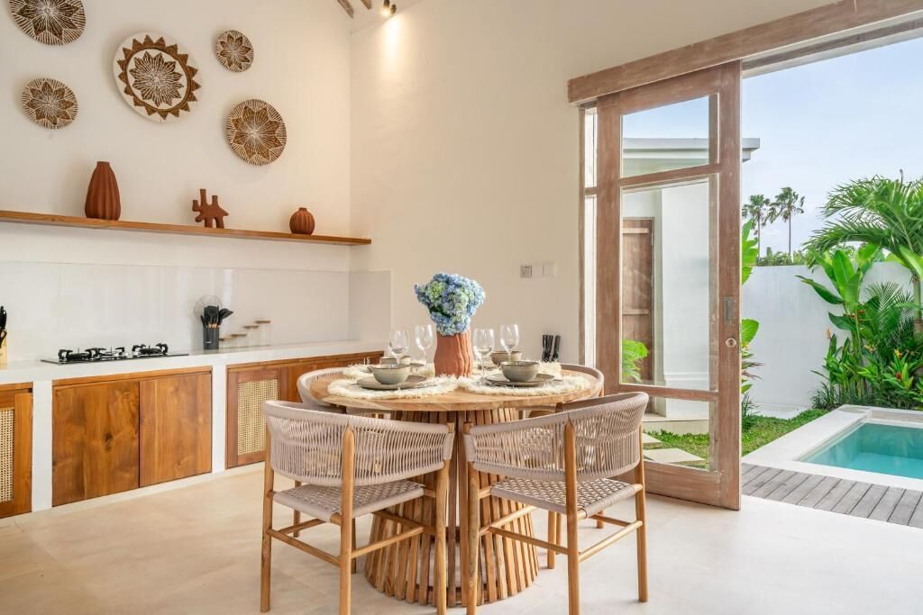 Cozinha moderna com mesa de jantar redonda, cadeiras de vime e pratos decorativos na parede.