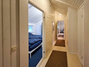 Ein schmaler Flur mit einem Bett und einer Tür zu einem anderen Zimmer.
