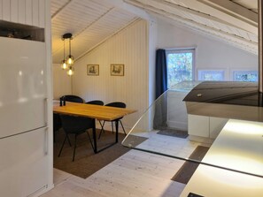Eine kompakte Küche mit Essbereich, Holzboden und einem fenster mit Vorhängen.