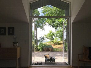 A room with a large sliding glass door leading to an outdoor patio with a bench and potted plants. - Architect-designed house with private beach (Løgstrup)